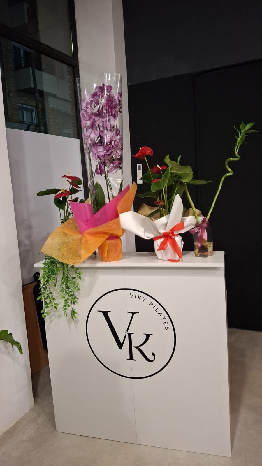 Recepción de Viky Pilates con el logo VK y flores de inauguración
